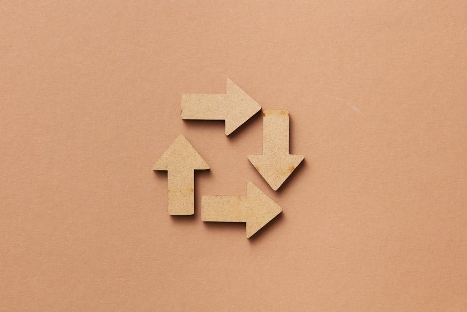 Close-up of a recycling symbol made from wooden arrows on a beige background.