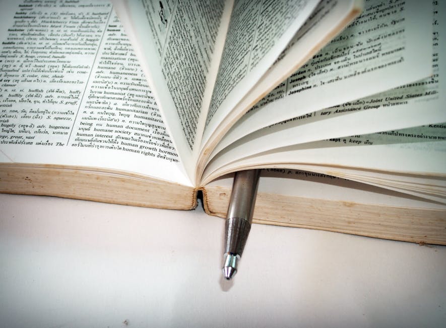 A close-up of an open dictionary with a pen separating the pages for convenient reference.